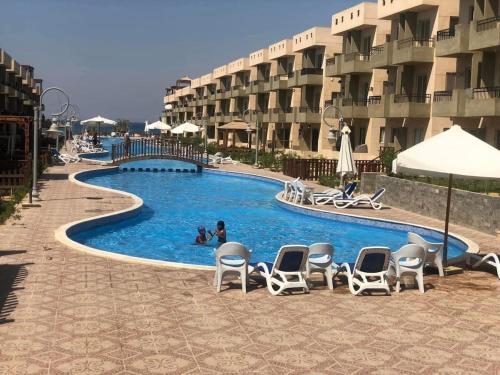 a swimming pool with chairs and people in a hotel at Tavera Ras Sudr in Makman