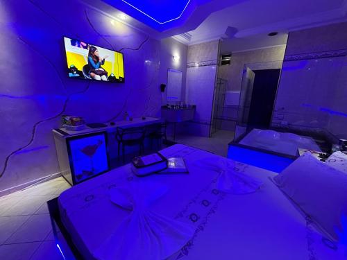 a purple room with two beds and a tv at Motel Maramores in Ribeirão Pires