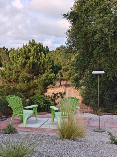 two green chairs sitting on a patio with trees at Casinhas Vale de Mouro in Melides