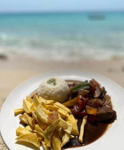 a plate of food with meat and chips and rice at Hostel bunker Peruano in Playa Blanca