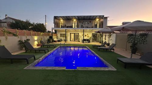 ein Haus mit einem blauen Pool vor einem Haus in der Unterkunft Olivia Estate South Corfu in Bastátika