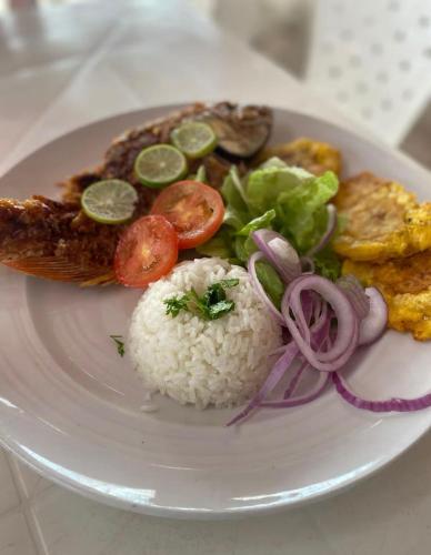 a white plate of food with rice and vegetables at Hostel bunker Peruano in Playa Blanca