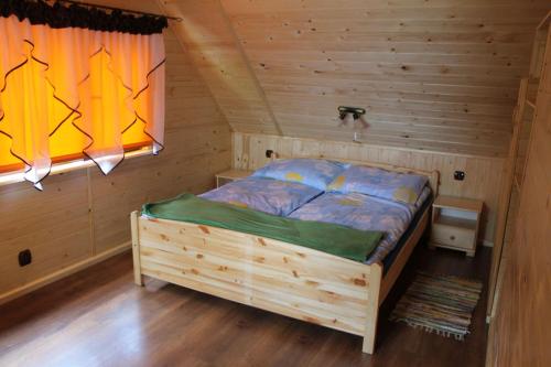 a bedroom with a bed in a wooden room at Domek Letniskowy Monika in Jeziorowskie