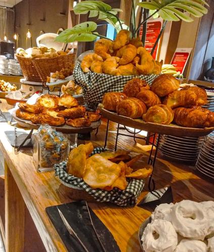 a buffet with several trays of bread and pastries at Hilton Garden Inn Tucuman in San Miguel de Tucumán