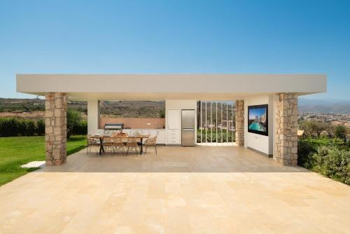 an outdoor patio with a table and a kitchen at Tholaria Villa in Chania