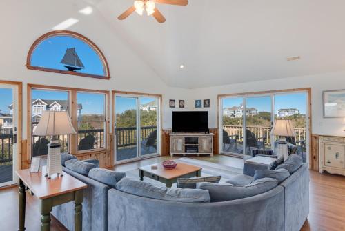 a living room with a large couch and a tv at Sea-renity in Corolla