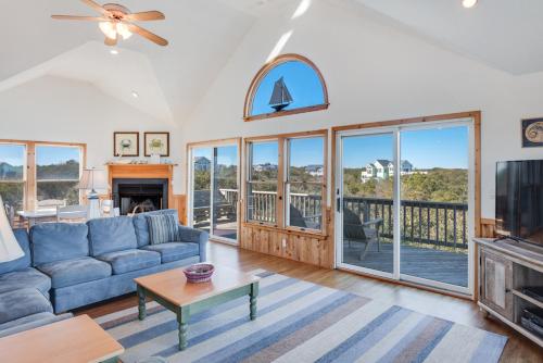 a living room with a blue couch and a tv at Sea-renity in Corolla