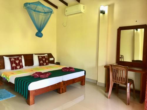a bedroom with a bed with a mirror and a chair at Darshani Lodge in Sigiriya