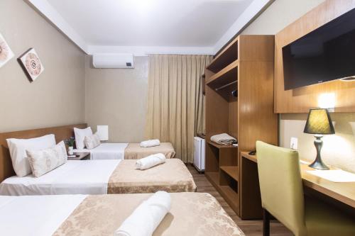a hotel room with two beds and a desk at Amuarama Hotel in Fortaleza