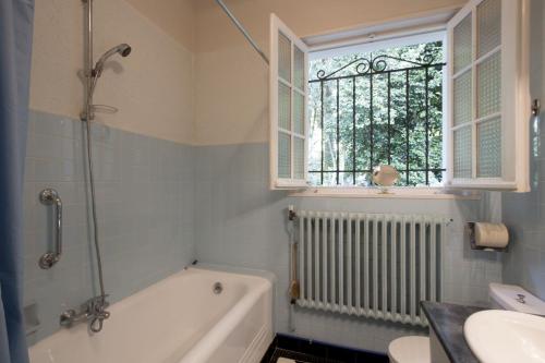 une salle de bain avec une baignoire, un lavabo et une fenêtre dans l'établissement Maison dans un écrin de verdure, à Biarritz