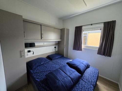 a bedroom with a bed with blue sheets and a window at Waddenlodge Deluxe in Harlingen