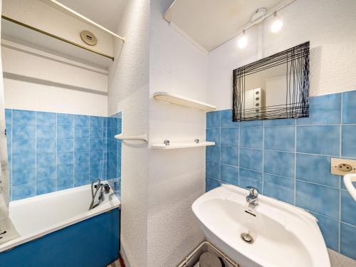 La salle de bains est pourvue de carrelage bleu, d'un lavabo et d'une baignoire. dans l'établissement Studio cosy 26m² - Pied des pistes - 4 pers - FR-1-807-26, à Saint-François-Longchamp