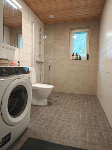 a bathroom with a washing machine and a toilet at Kampuksen Hertta in Pori