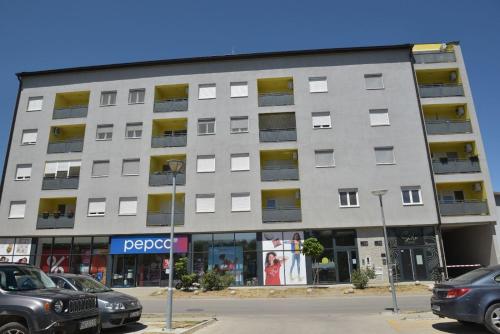 a large building with cars parked in front of it at Kutak M in Bečej