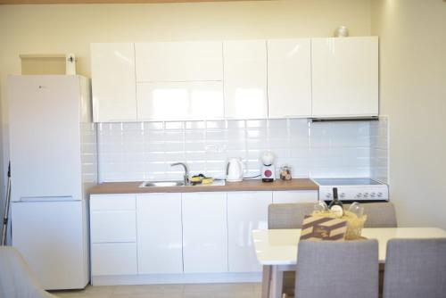 a kitchen with white cabinets and a white refrigerator at Kutak M in Bečej