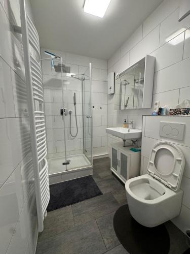 a white bathroom with a shower and a toilet at Modernes Zimmer am Campus 3 mit Gemeinschaftsbad in Villingen-Schwenningen