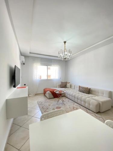 a white living room with a couch and a tv at Shams luxury home in Martil
