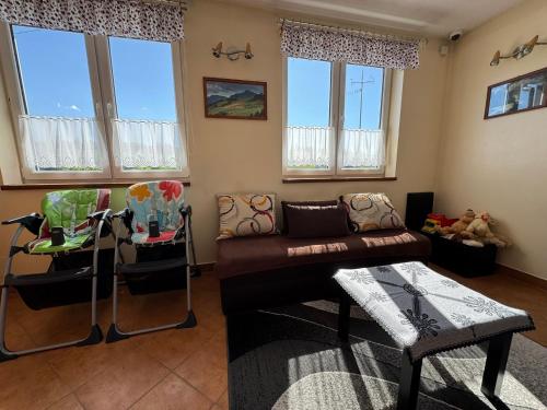 a living room with a couch and some windows at Willa Modra in Bukowina Tatrzańska
