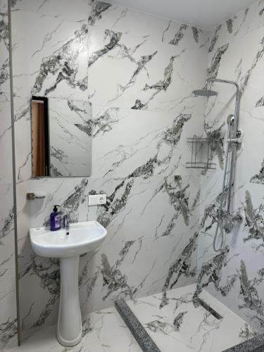 a white bathroom with a sink and a mirror at Mirza Guesthouse in Batumi