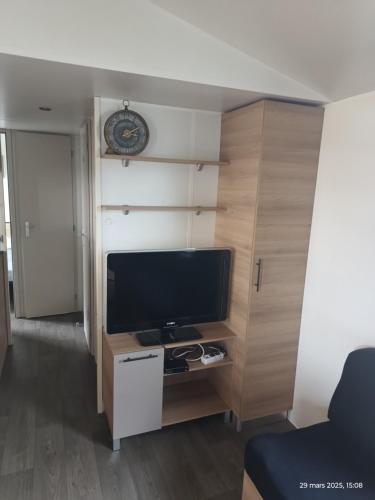 a living room with a flat screen tv on a cabinet at Camping les sables du midi à Valras plage in Valras-Plage