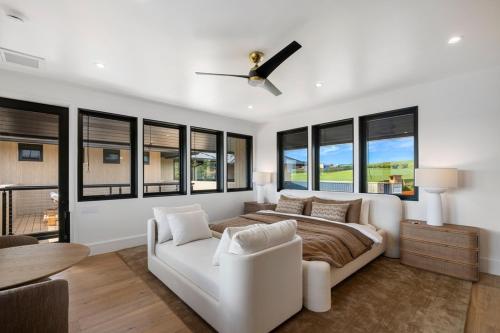 a bedroom with a bed and a couch and windows at Hale O Ka Nene in Koloa