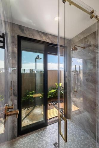 a bathroom with a glass shower with a view at Hale O Ka Nene in Koloa
