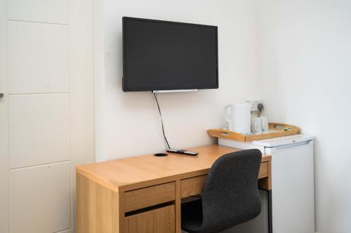 a desk with a chair and a television on a wall at London City Hotel in Woolwich