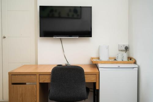 a desk with a chair and a television on a wall at London City Hotel in Woolwich