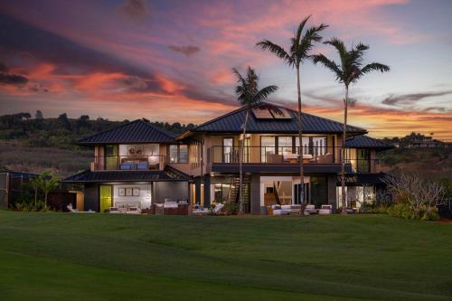 a house with palm trees and a sunset at Hale O Ka Nene in Koloa