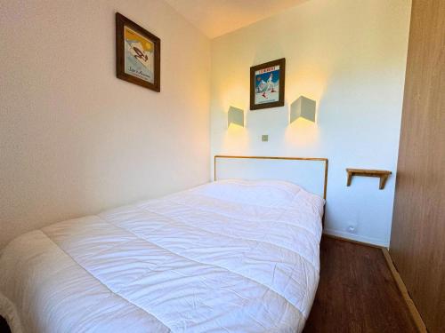 - un lit dans une chambre avec 2 photos sur le mur dans l'établissement Appartement confort pour 4 pers, en bord de pistes avec balcon, animaux admis - FR-1-452-265, aux Menuires