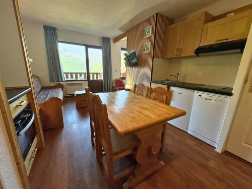 une cuisine avec une table en bois et une salle à manger dans l'établissement Appartement confort pour 4 pers, en bord de pistes avec balcon, animaux admis - FR-1-452-265, aux Menuires