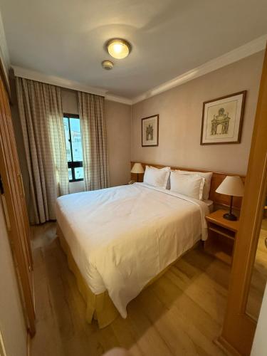 a bedroom with a large white bed and a window at Dream Flat Pinheiros in Sao Paulo