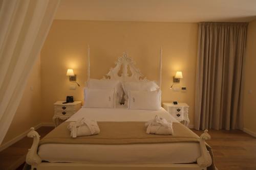 a bedroom with a large white bed with towels on it at Quinta da Maquia Hotel in Sintra