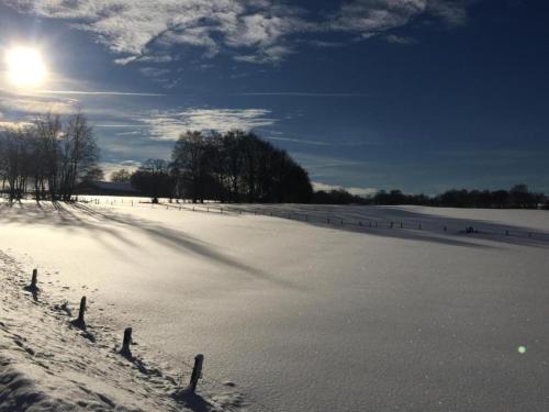 a field covered in snow with the sun in the sky at Apartment in Halenfeld-Amel with Terrace in Amblève