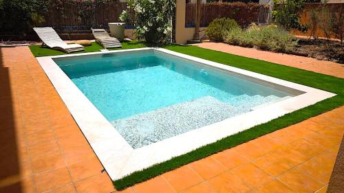 a swimming pool in a yard with two lawn chairs at Historic House at Can Quintana by Casa de Elena in Pineda de Mar