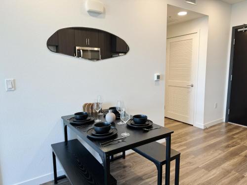 ロサンゼルスにあるModern 1BR Apartment with Pool, Hot Tub and Gym Access 10mins to Universal Studiosのダイニングルーム(黒いテーブル、鏡付)