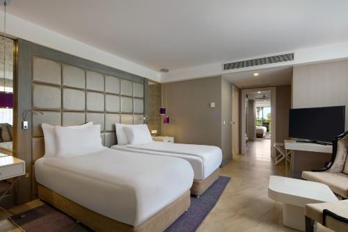 a hotel room with two beds and a television at TUI Magic Life Rixos Beldibi - Adult Only in Beldibi