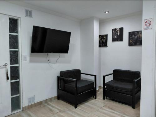 a living room with two chairs and a flat screen tv at Caleta Olivia Ancla alojamiento departamento in Caleta Olivia