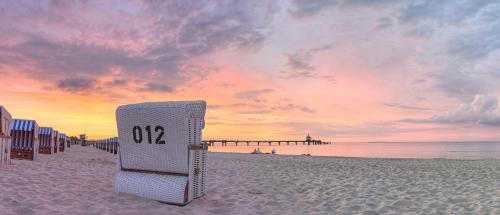 a sign on a beach with a pier in the background at BeltBlick 19 – Exklusive Ferienwohnung mit Garten und Meerblick in Fehmarn