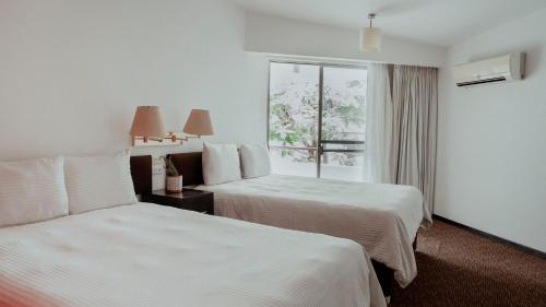 a hotel room with two beds and a window at Hotel San Felipe in Oaxaca City