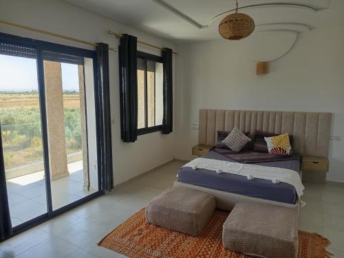 a bedroom with a bed and a large window at Lina Village in Al Hachlaf