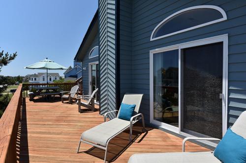 a deck with chairs and a table with an umbrella at My Happy Place by Village Realty in Corolla