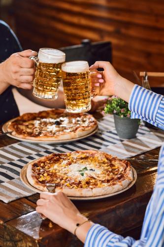 a group of people sitting at a table with two pizzas at Hotel Selce in Selce