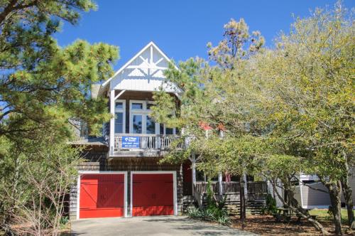 a house with red doors and a balcony at Reminiscent in Nags Head