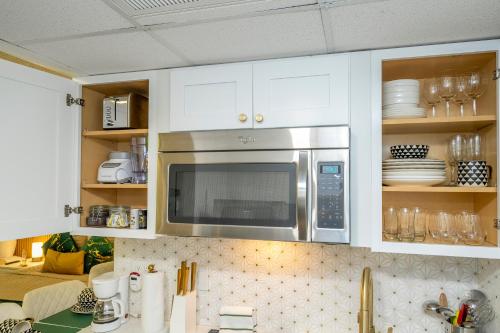 a kitchen with white cabinets and a microwave at Emerald Luxe Lakeview 6 min to EPIC Universe in Orlando