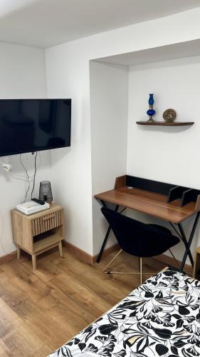 a room with a desk and a television and a chair at Le Minaouët Studio Confort Gare Rosporden in Rosporden