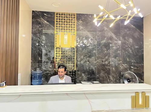 a man sitting at a desk in a lobby at Elysium Tower Premium Hotel Serviced Apartments Islamabad in Islamabad