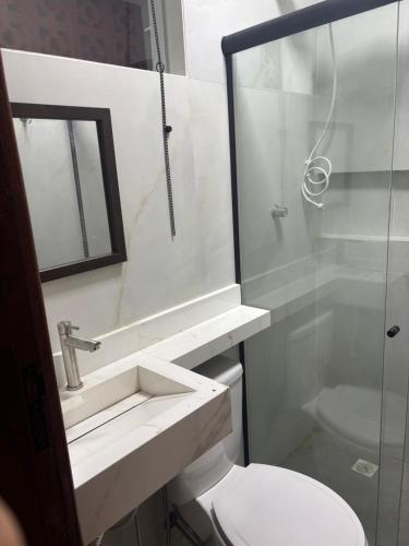 a white bathroom with a sink and a toilet at Pousada Beatriz - Búzios in Búzios