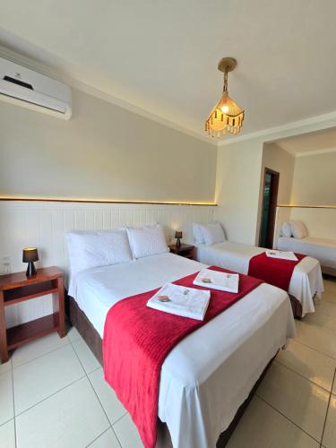 two beds in a hotel room with a red blanket at Navega Hotéis in Navegantes
