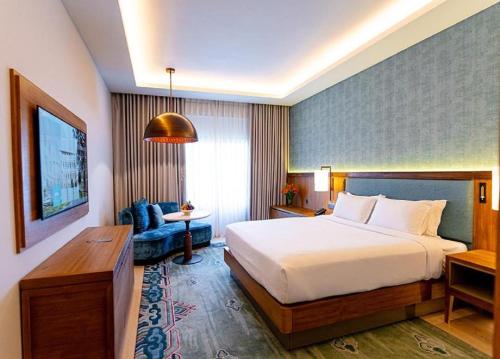 Una habitación de hotel con una cama grande y un sofá. en Hotel Eureka International Near Delhi Airport, en Nueva Delhi